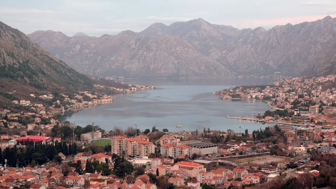 The Bay of Kotor seen from above, a blue fjord ringed by steep grey mountains in Montenegro