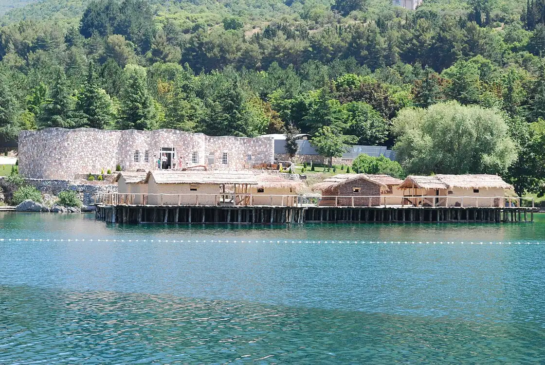 The row of Bay of Bones houses standing on a dense field of wooden piles rising out of Lake Ohrid