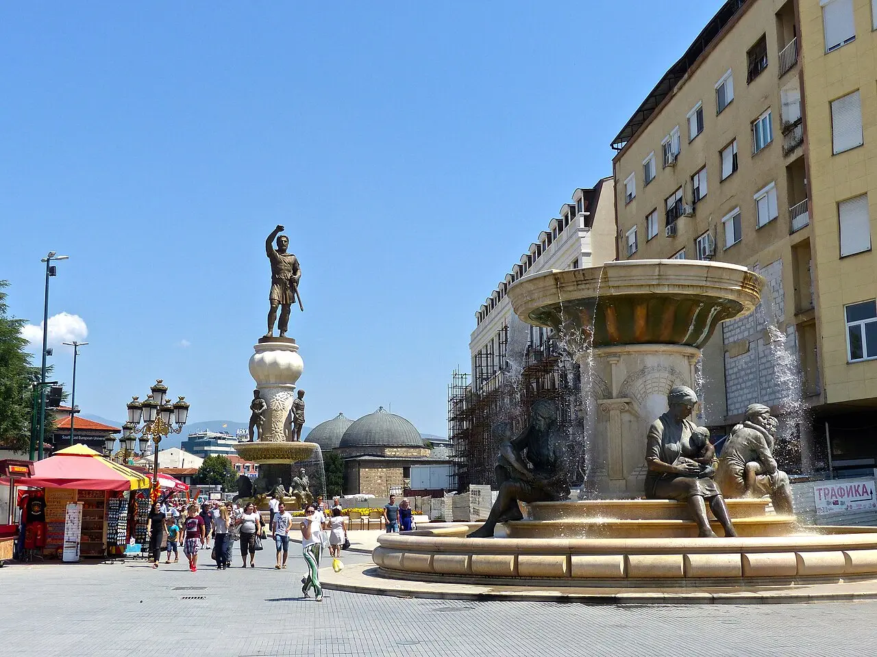 A busy square in central Skopje with kiosks, shops and people walking