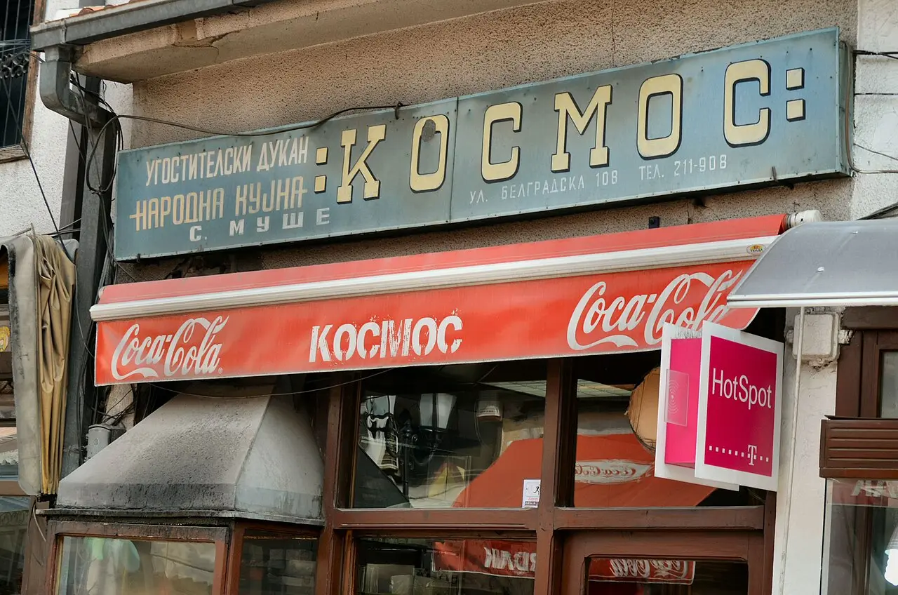 An old Skopje shopfront with a hand-painted sign and a magenta Telekom HotSpot plate
