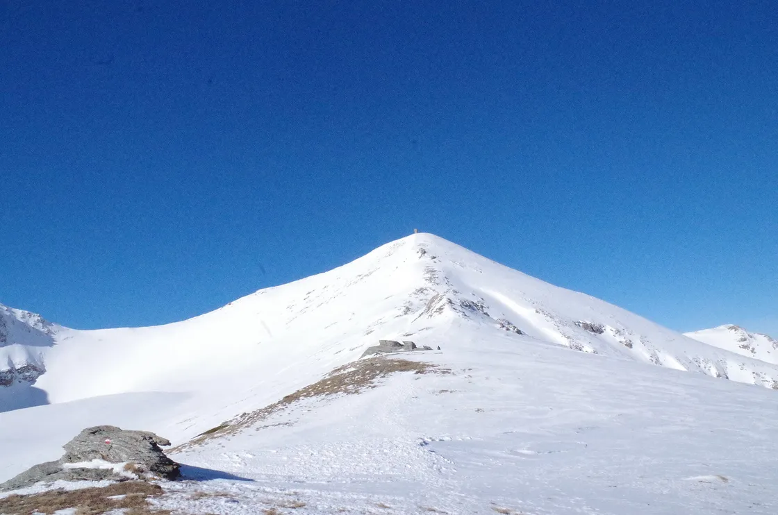 The snow-covered pyramid summit of Titov Vrv in the Šar Mountains under a deep blue sky