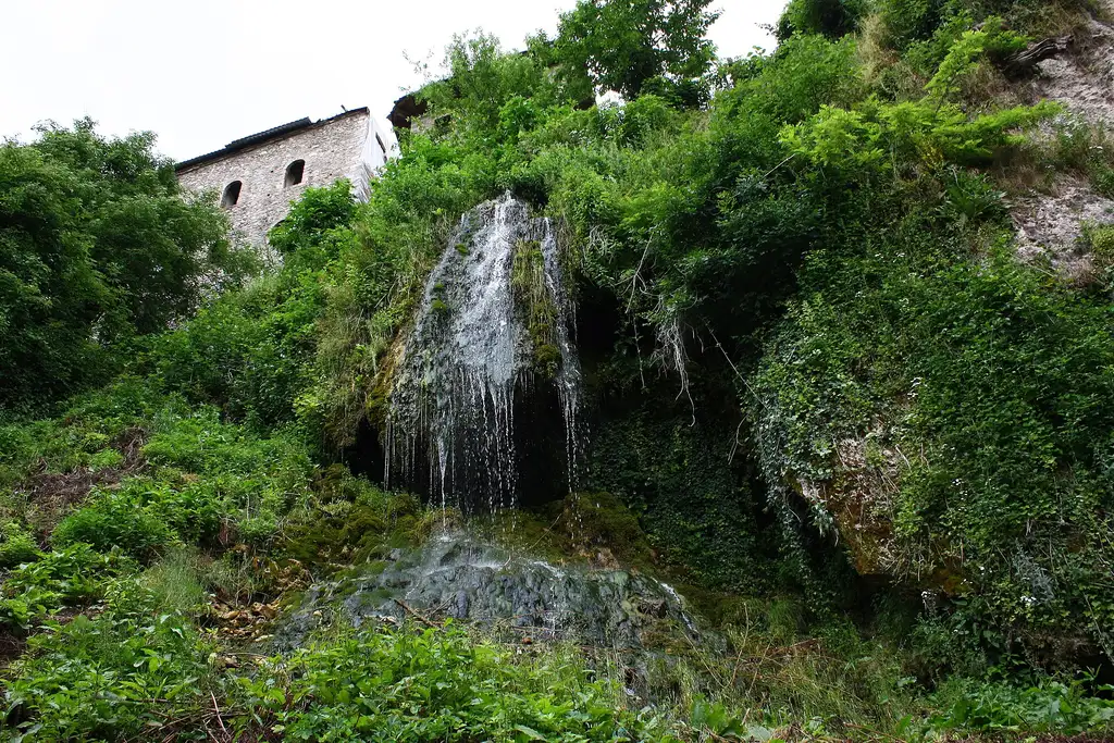 A spring falling over a mossy travertine shelf on the hillside below the monastery walls
