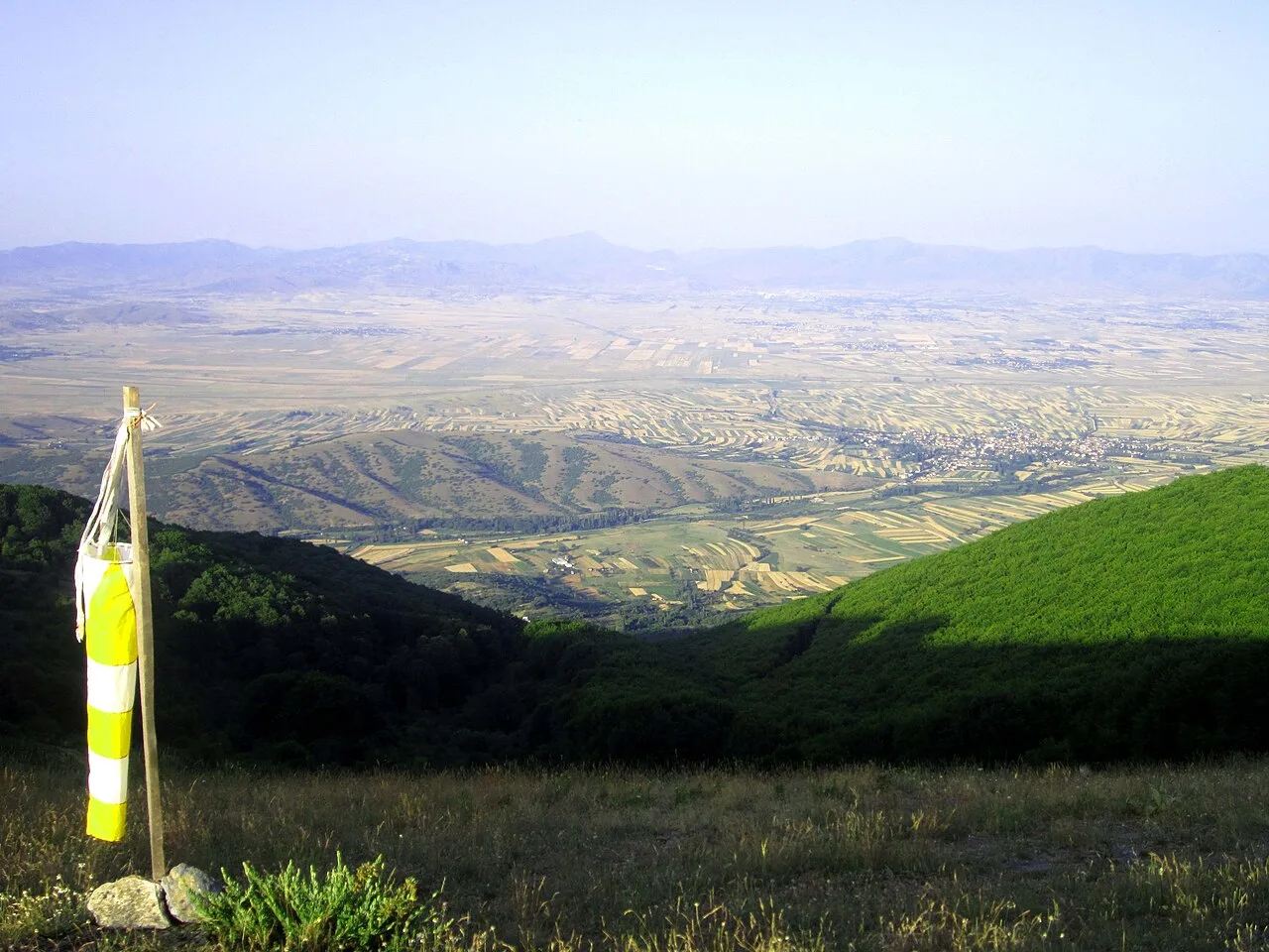 The wide Pelagonia plain seen from a mountain overlook, farmland stretching toward distant hills between Bitola and Prilep