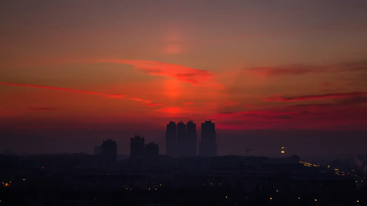 Sunrise over residential tower blocks and hills in Skopje seen from a high-rise balcony