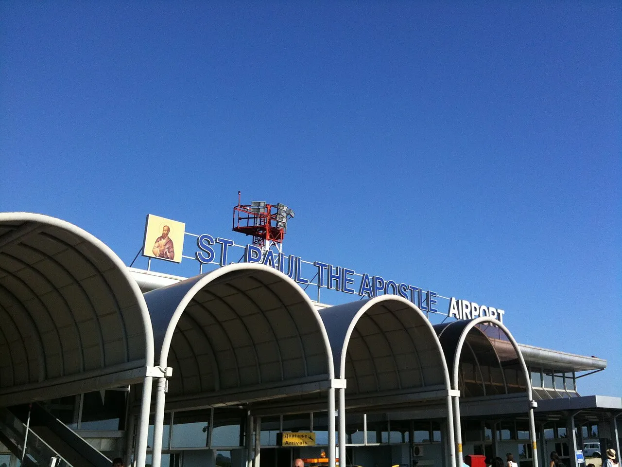 The curved white roof and signage of St Paul the Apostle Airport at Ohrid against a deep blue sky