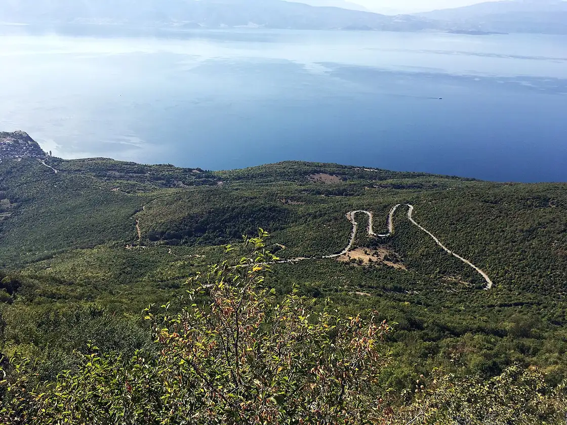 Hairpin bends of the Galicica mountain road cutting through green scrub high above the blue water of Lake Ohrid