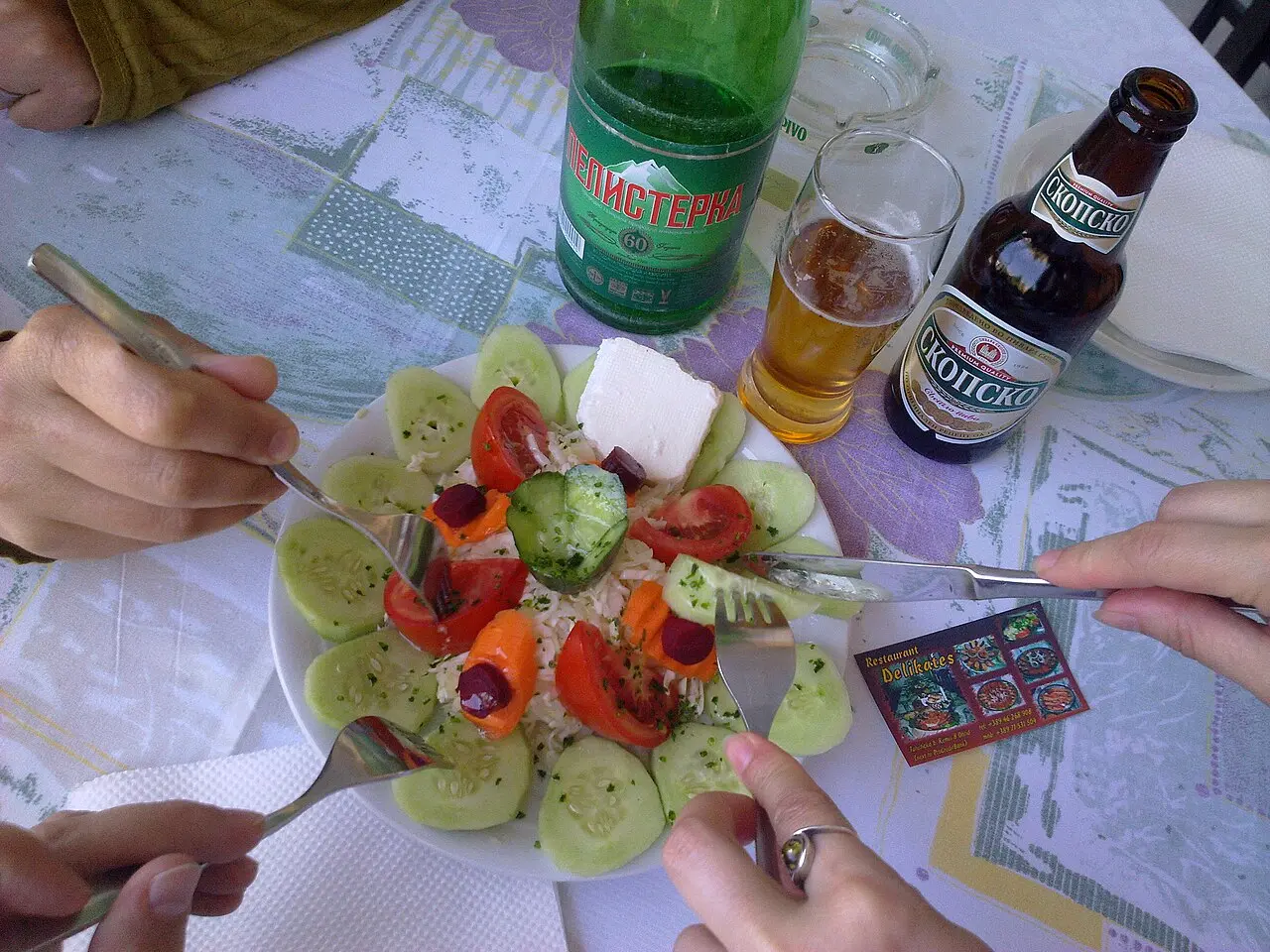 Friends sharing a salad and bottles of Skopsko beer at an outdoor café table in Ohrid