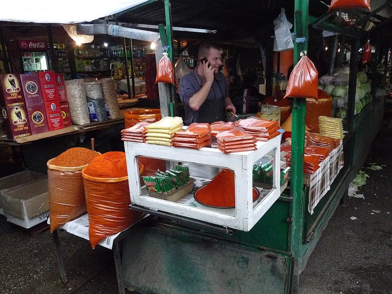 A stallholder at Bit Pazar in Skopje sitting among sacks of dried red peppers