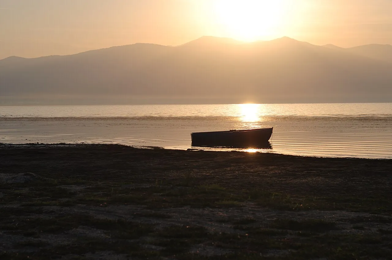 A wooden boat at sunrise on the calm water of Lake Prespa at Oteševo