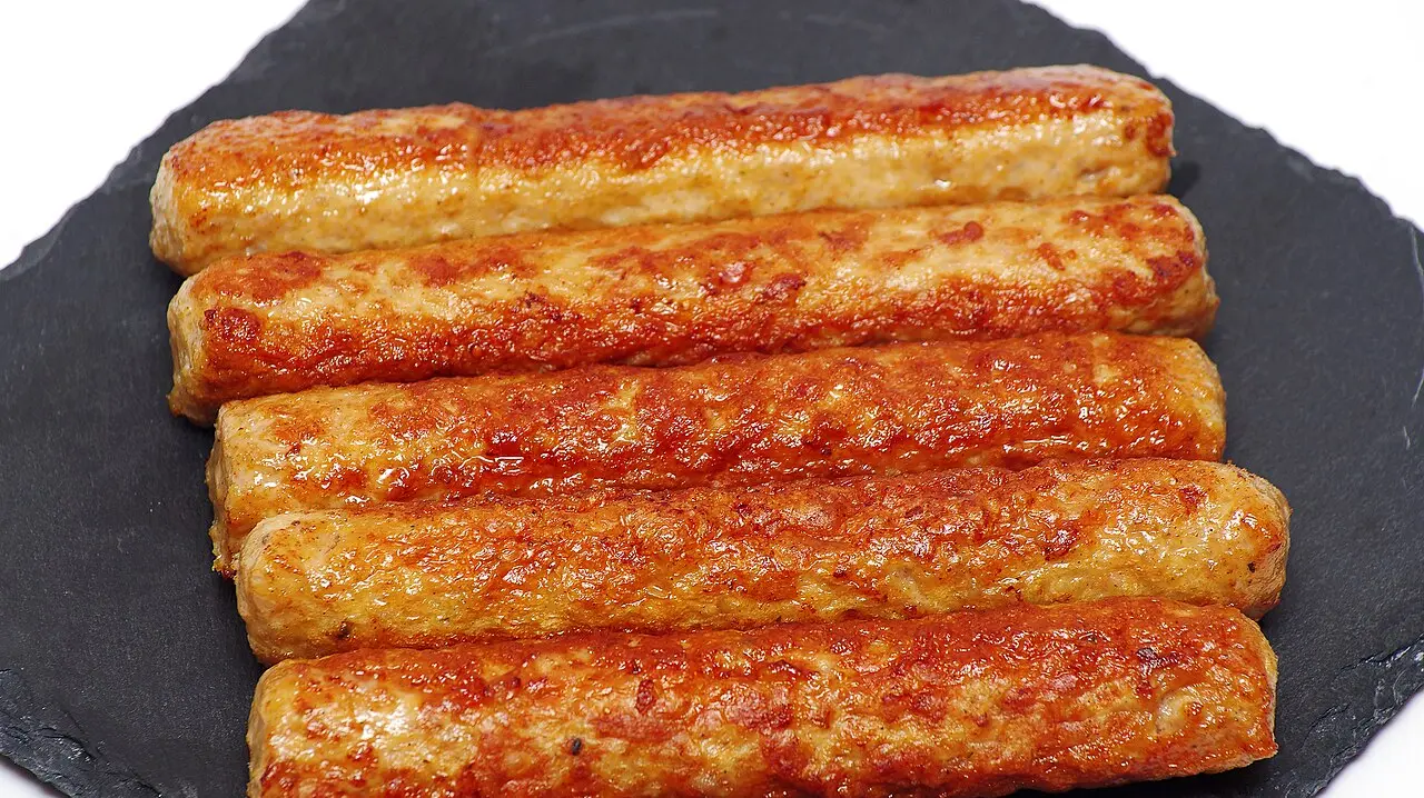 Grilled kebapi (ćevapi) - small minced-meat rolls on a dark slate board