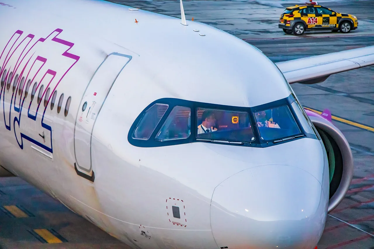 A Wizz Air Airbus A321neo on the apron in the airline's pink and purple colours