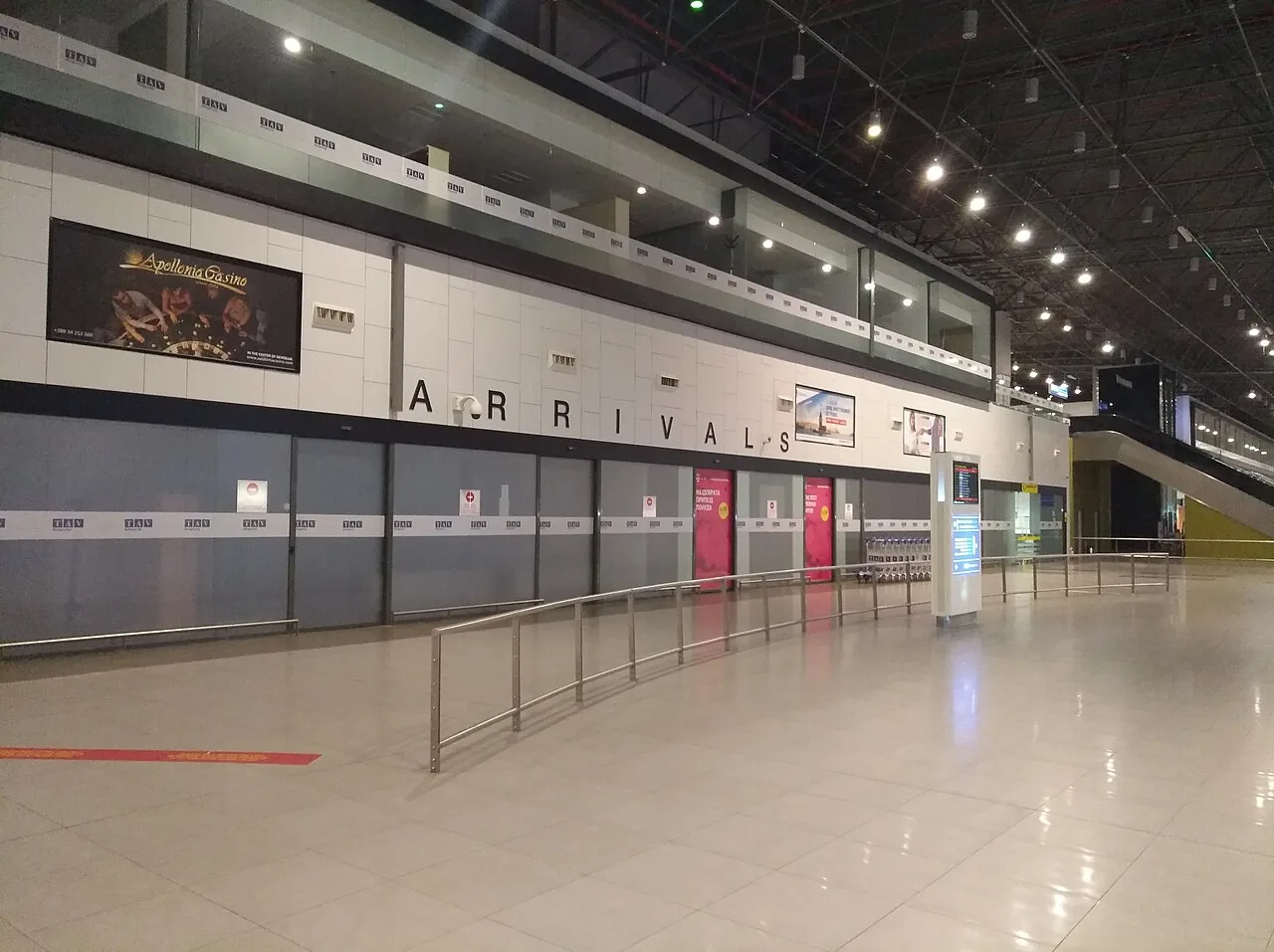 Arrivals hall at Skopje International Airport with passengers and shops