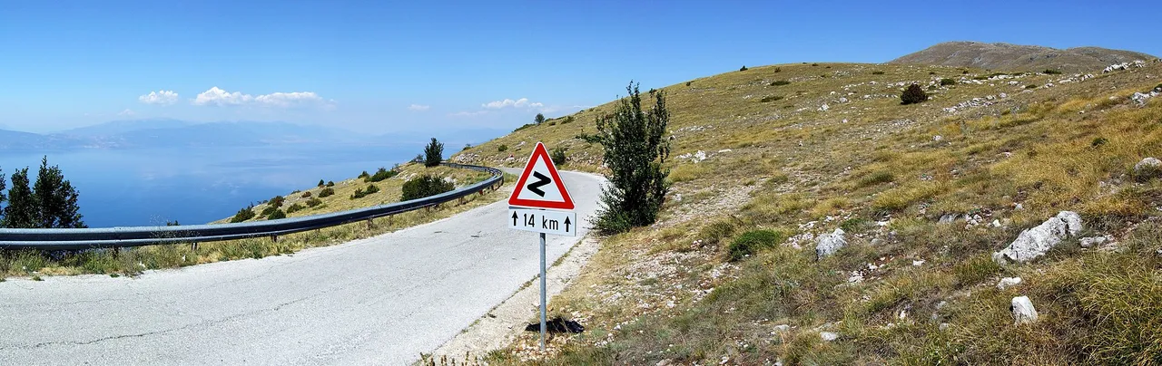 The narrow asphalt pass road curving across the bare upper slopes of Galičica with Lake Ohrid far below