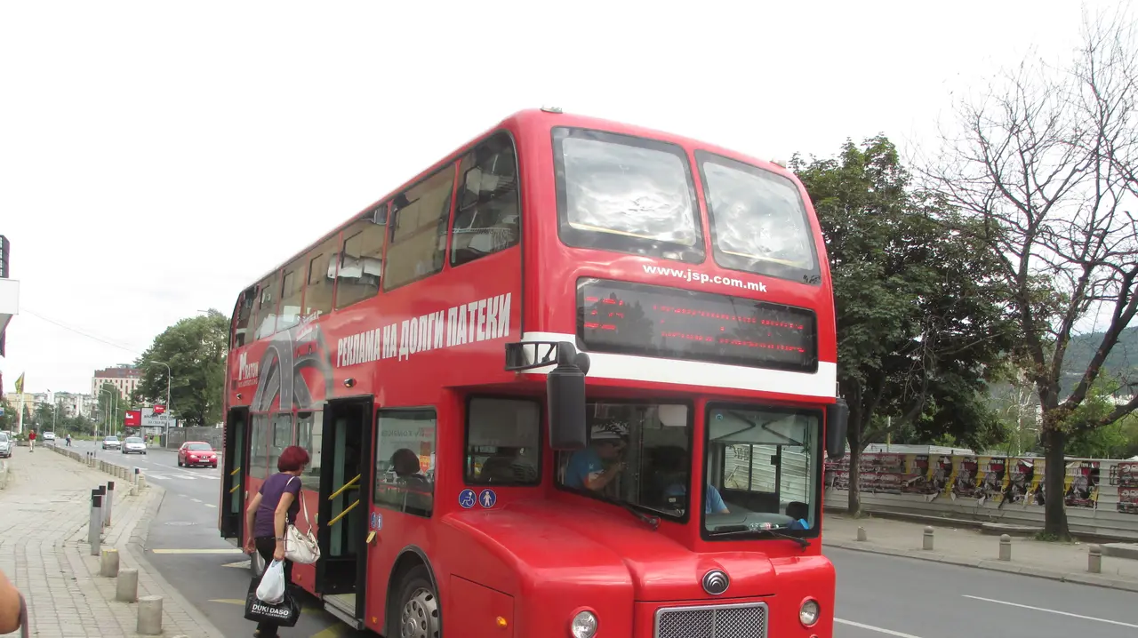A red double-decker city bus on a street in central Skopje