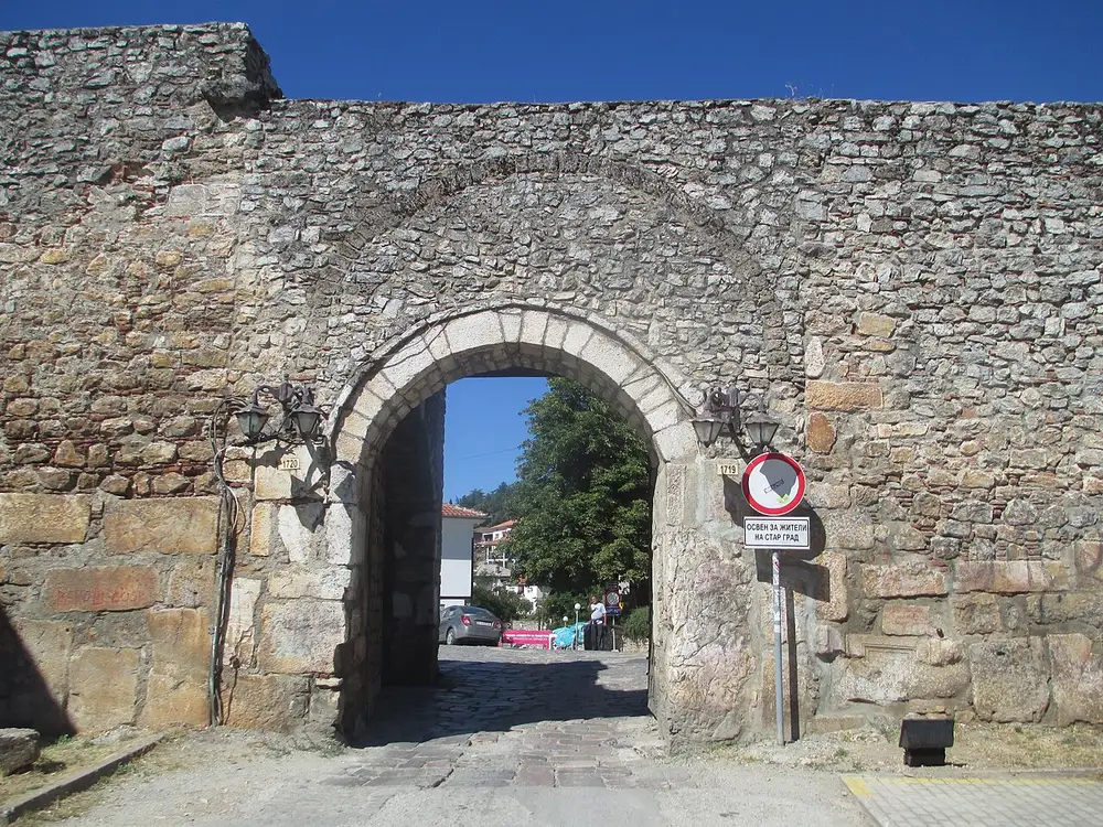 A stone medieval gate in the old town wall of Ohrid under a bright blue sky