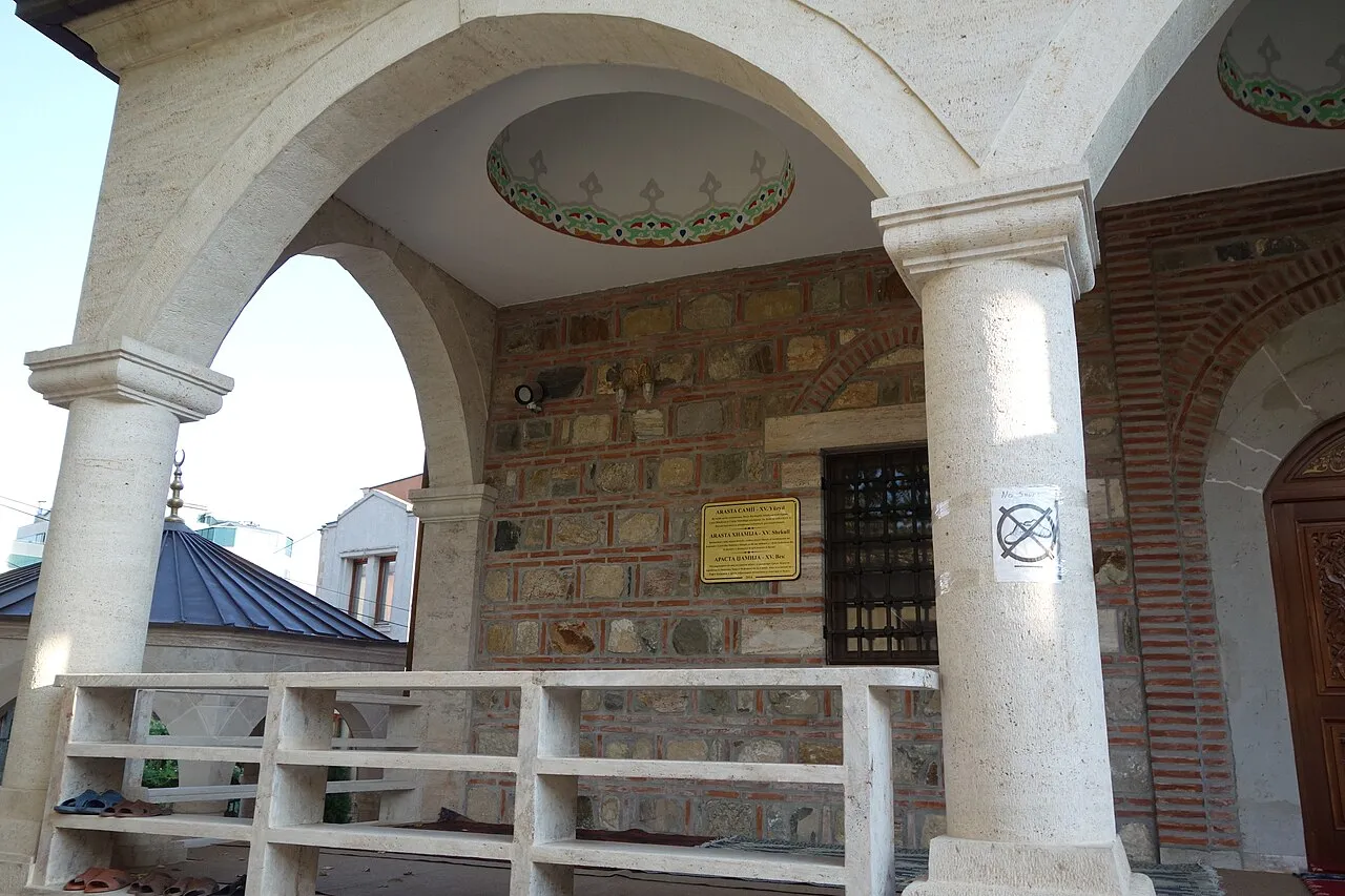 A cobbled lane of the Old Bazaar in Skopje lined with low shopfronts and a minaret beyond