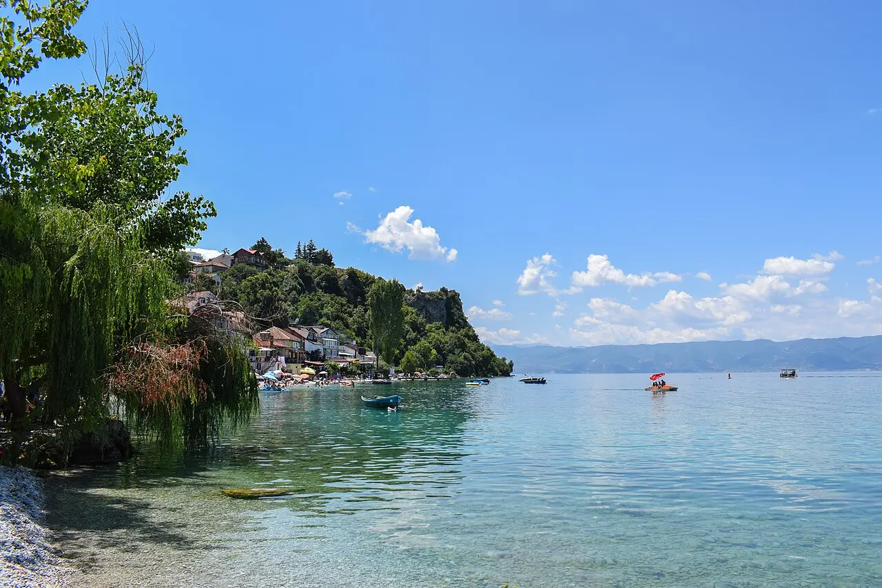 Swimmers and sunbeds on a small pebble beach at Trpejca on Lake Ohrid in summer