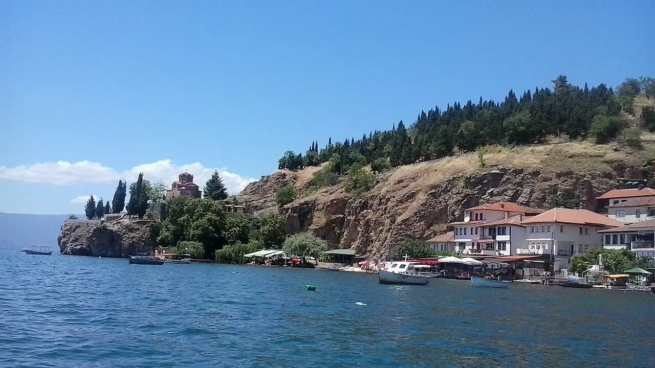 The cliff-top Church of St. John at Kaneo above the blue water of Lake Ohrid, with boats and lakeside houses