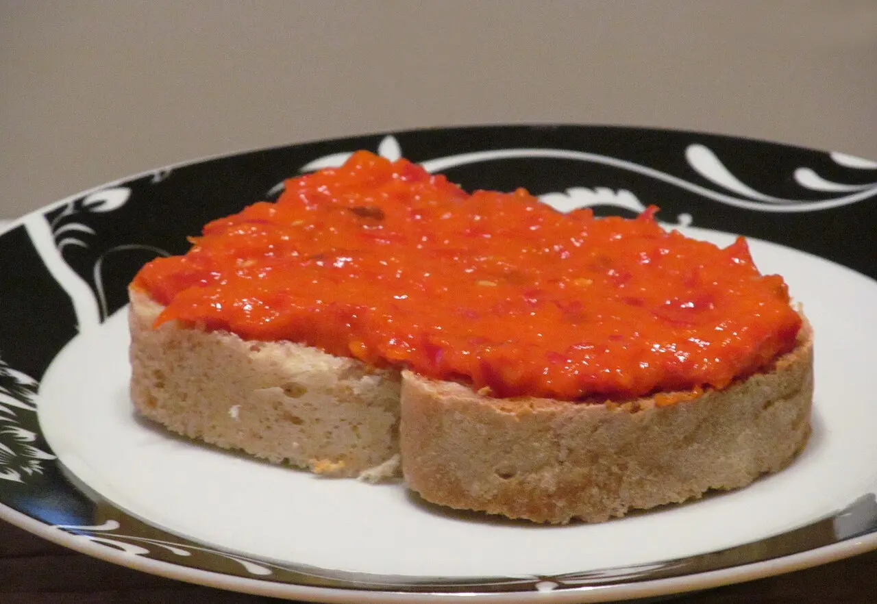 Ajvar, a red roasted-pepper relish, spread on a slice of bread on a plate