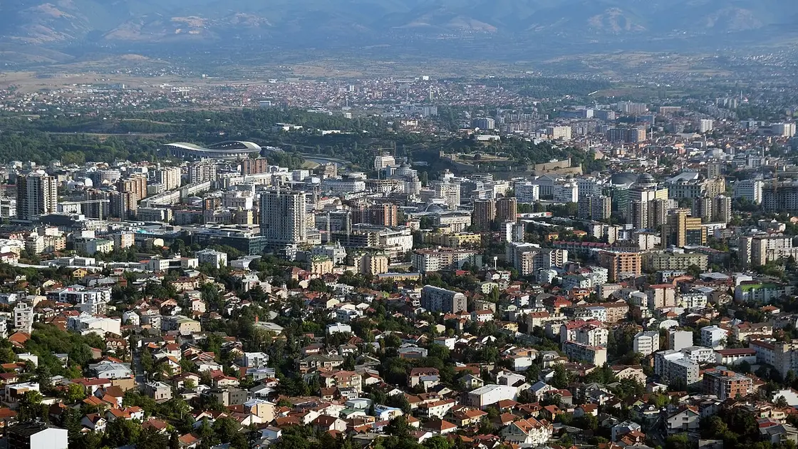 A wide view over Skopje with the Vardar river, city buildings and mountains behind