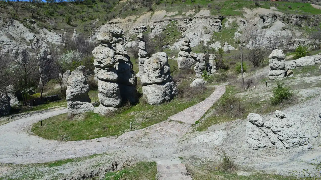 A hillside at Kuklica covered with pale eroded stone pillars above a dirt path