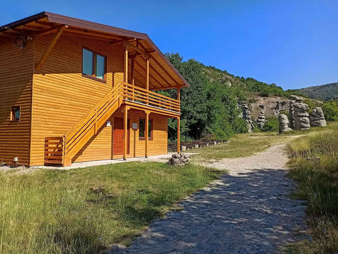 A stone-paved path at Kuklica leading past a wooden cabin towards the field of pillars