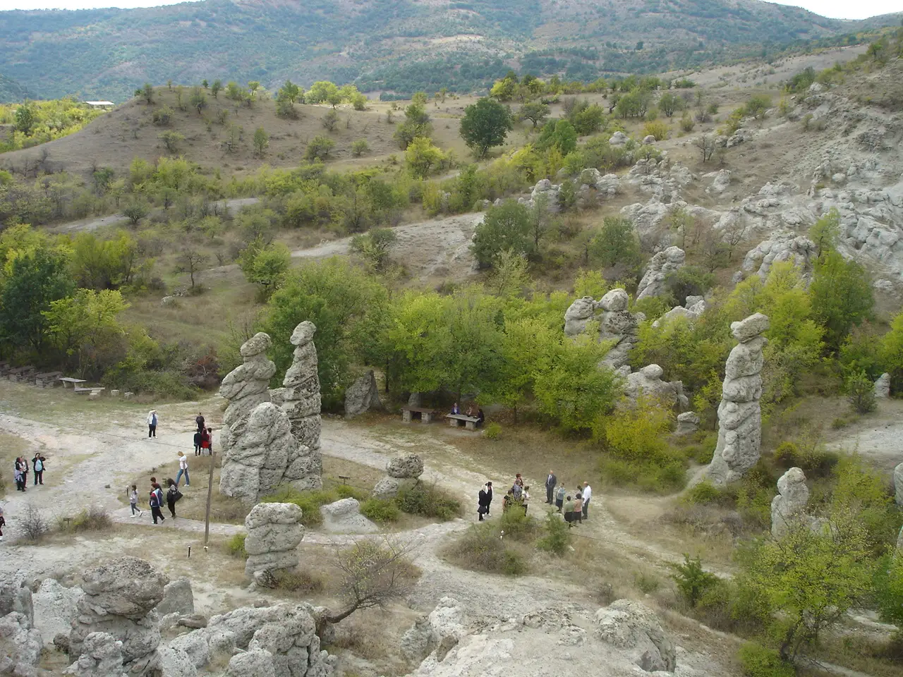 A group of visitors walking among the tall stone pillars of Kuklica, showing their scale