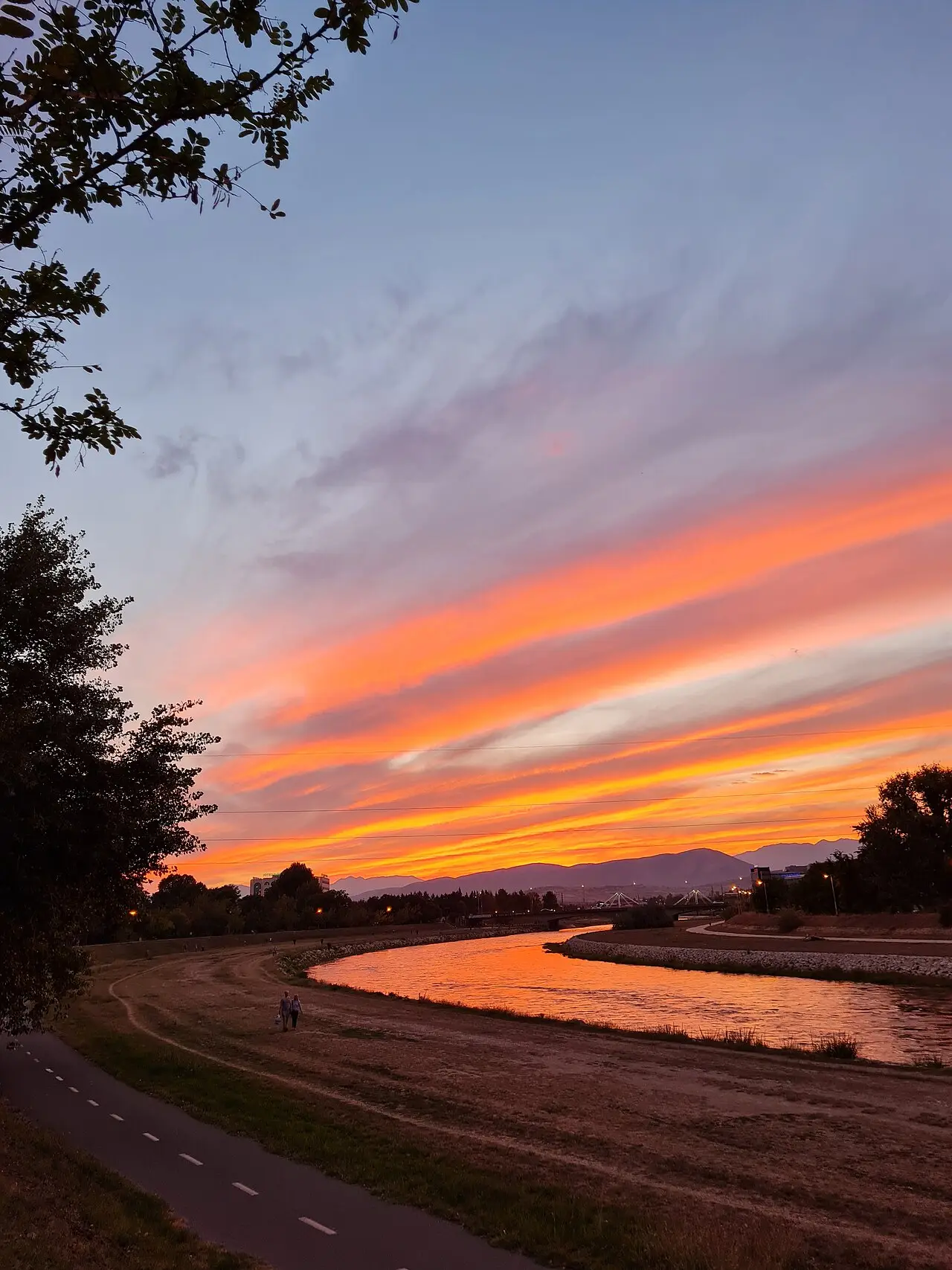 Orange sunset over the Vardar river in Skopje, with the riverside walking and cycling path in the foreground
