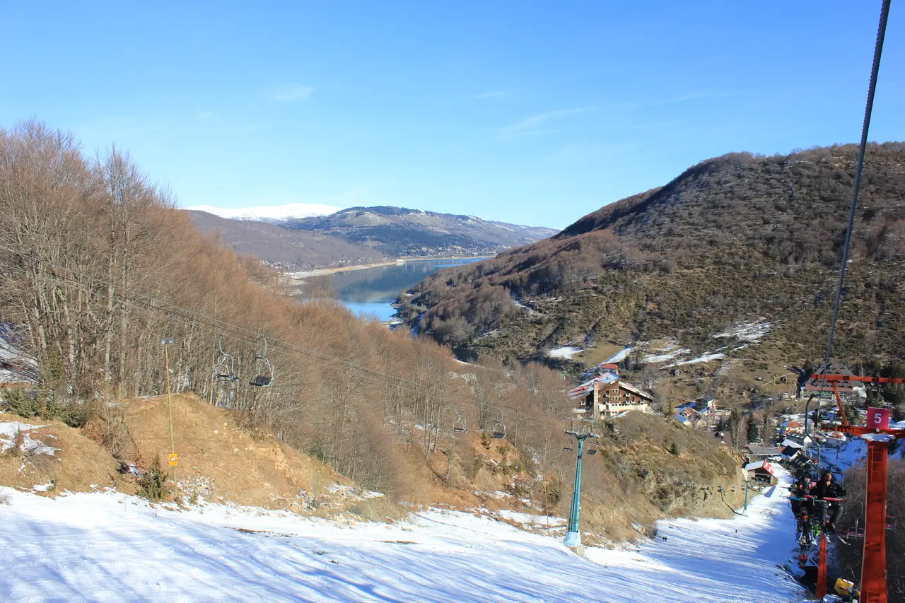 A ski slope and chairlift at the Mavrovo ski centre in winter, with the lake and mountains below