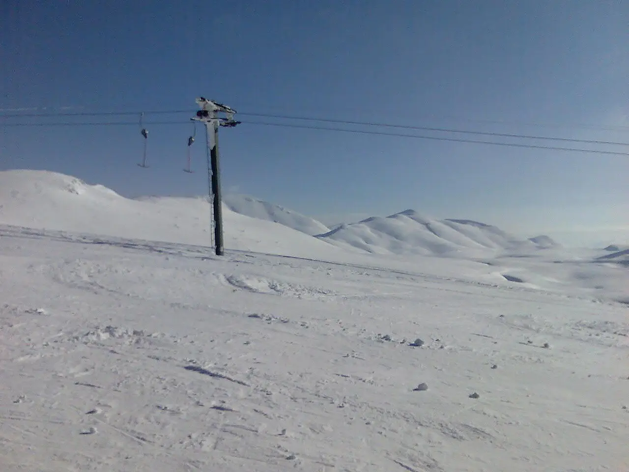 Broad open snow slope at Mavrovo with a lift pylon and mountains behind