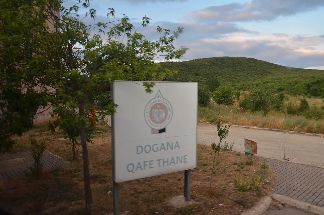 A white Albanian customs sign reading Dogana Qafe Thane, on the Albanian side of the Kjafasan / Qafe Thane crossing with North Macedonia