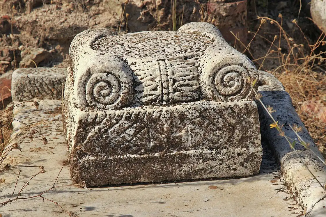 A carved stone Ionic capital with spiral volutes lying among the ruins of Heraclea Lyncestis near Bitola