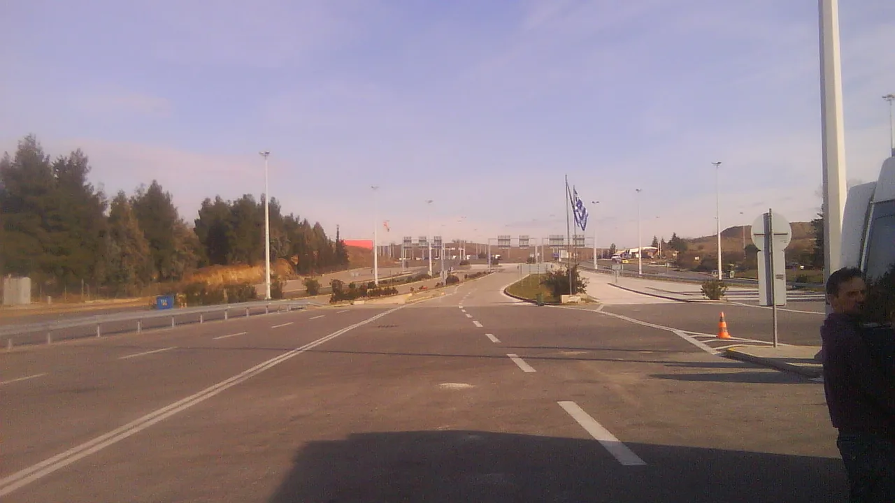 The approach road to the Bogorodica-Evzoni border crossing, with the Greek flag and the control canopies ahead