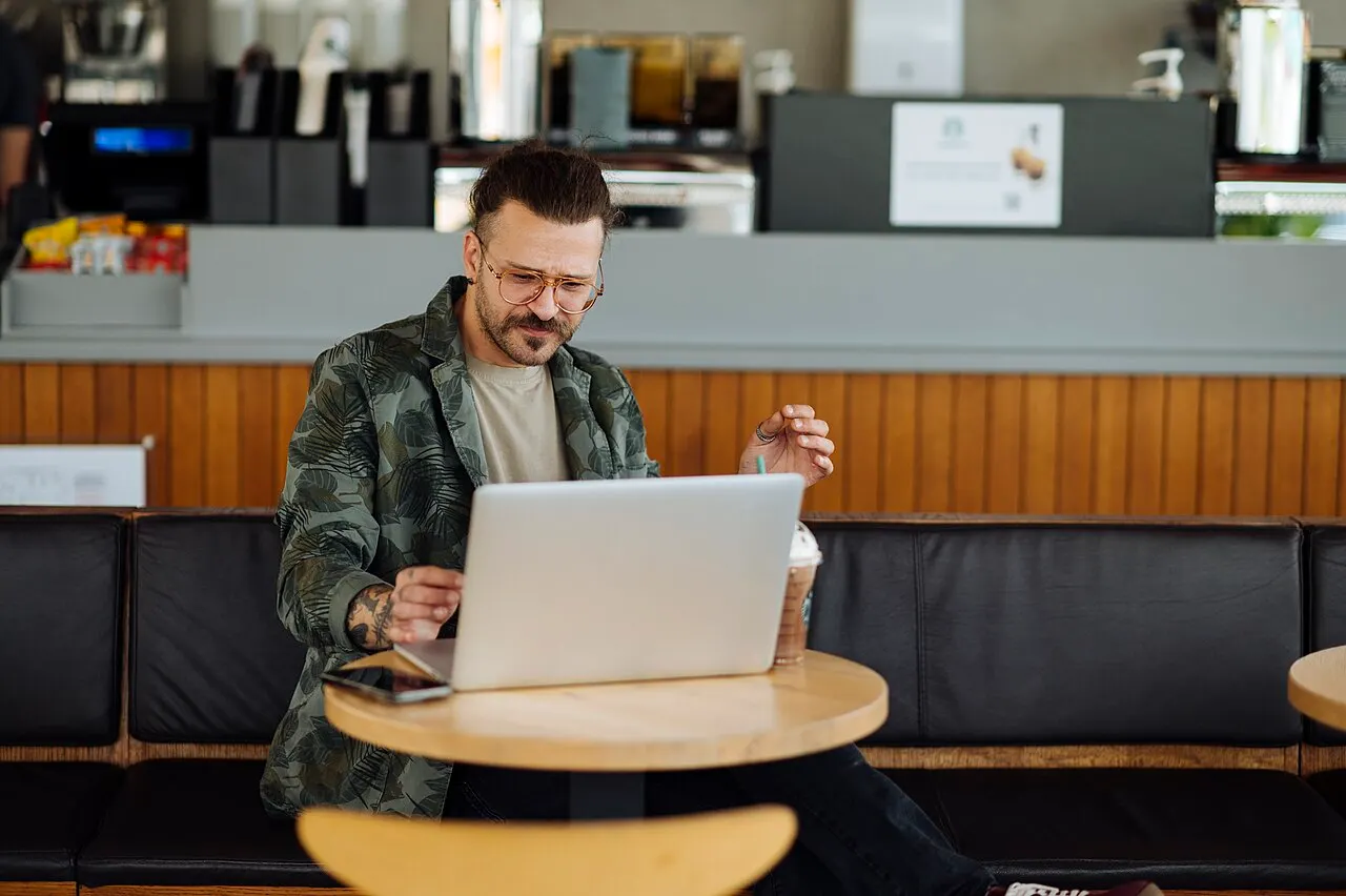 Person working on a laptop with a cup of coffee on the table in a cafe