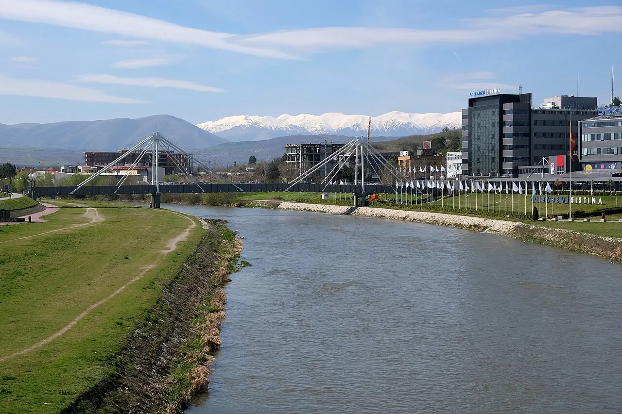 Pedestrian bridge over the Vardar river in Skopje with the riverside promenade