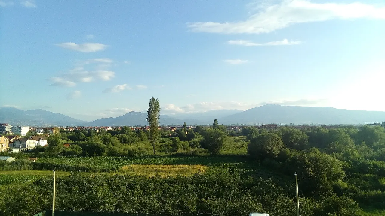 Green fields and red-roofed houses on the north shore of Lake Ohrid toward Struga, mountains beyond