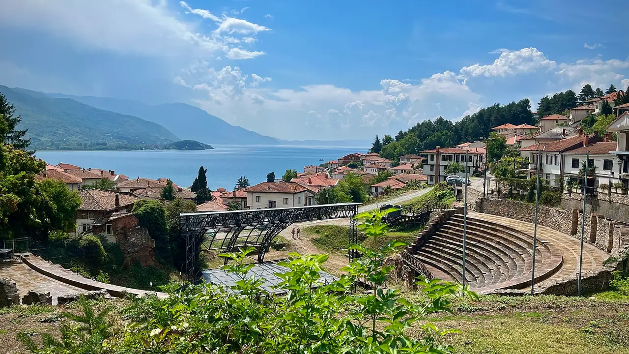 The restored stone tiers of the ancient theatre in Ohrid with the old town rooftops and Lake Ohrid behind on a summer day