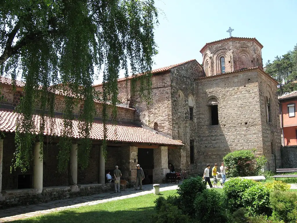 The 11th-century Church of St Sophia in Ohrid, a brick and stone building with a domed tower and a columned portico, seen across its garden courtyard