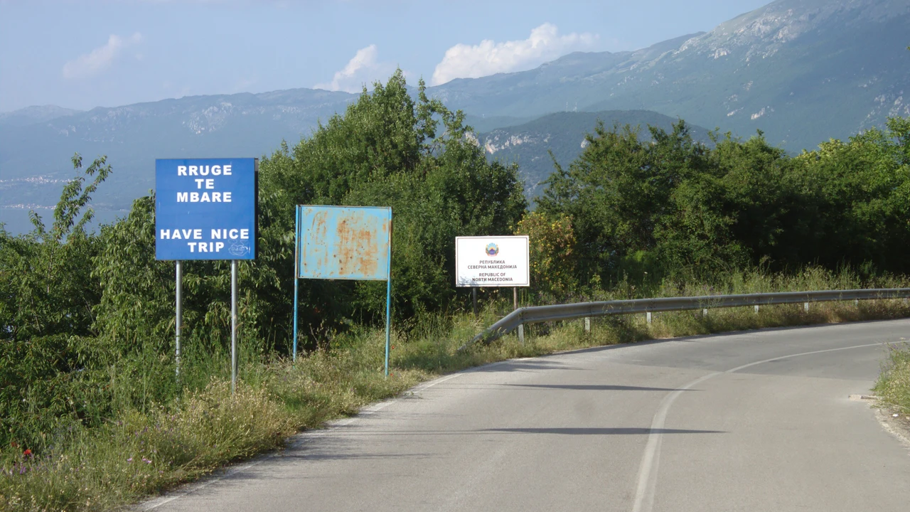 The road at the Sveti Naum border crossing with an Albanian farewell sign and a Republic of North Macedonia welcome sign