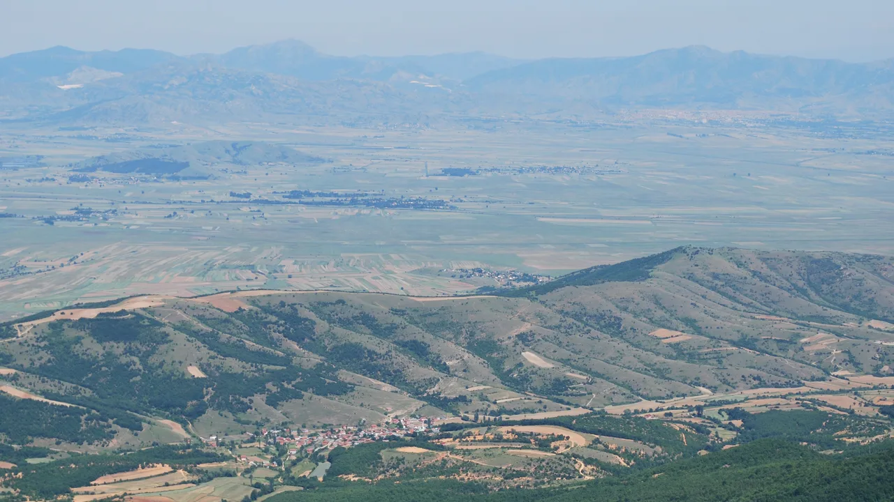 Looking down from the wooded hills above Kruševo onto Aldanci village and the flat Pelagonia plain, with mountains on the horizon