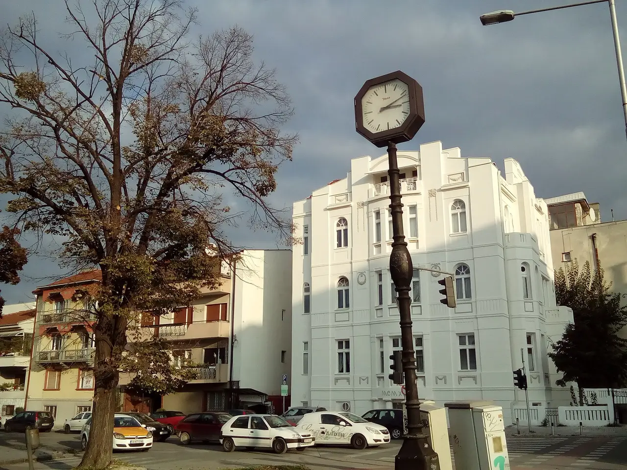 A white Ruben Palace on Ilinden Boulevard in Debar Maalo, Skopje, with a street clock and cars parked at its foot