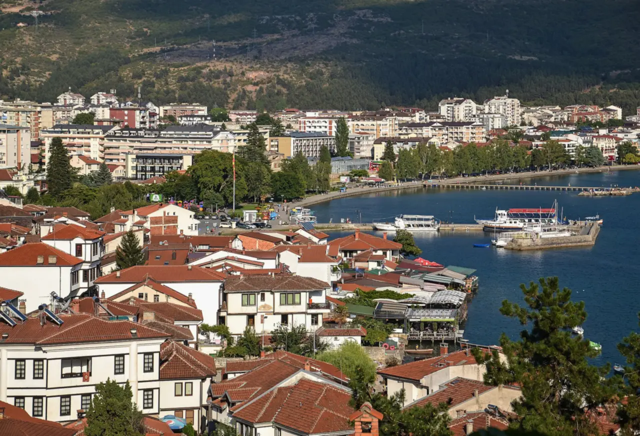 Red-tiled roofs of the old town of Ohrid above the harbour, with boats at the pier and the lakeside promenade curving away
