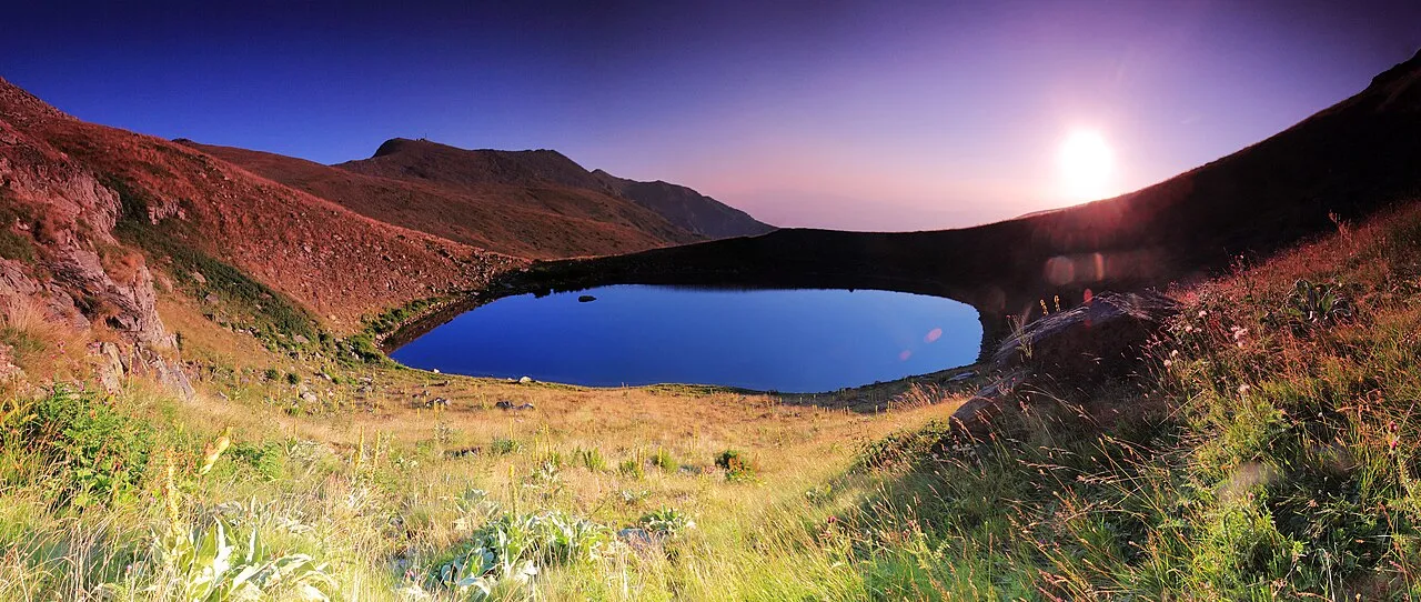 Malo Ezero, the Small Lake of Pelister, catching the first light of sunrise among grassy alpine slopes