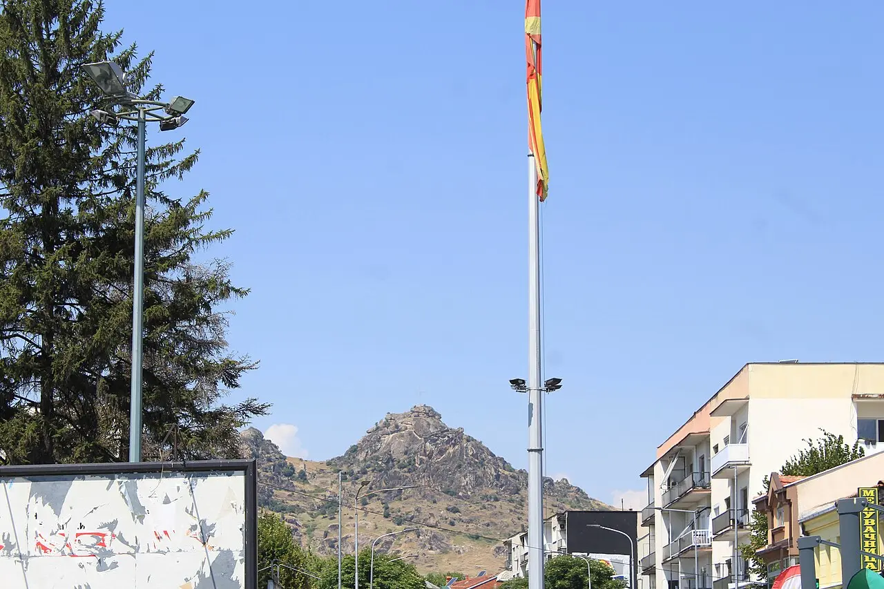 Prilep's main square with a flag, the boulder-crowned Markovi Kuli hill rising in the background