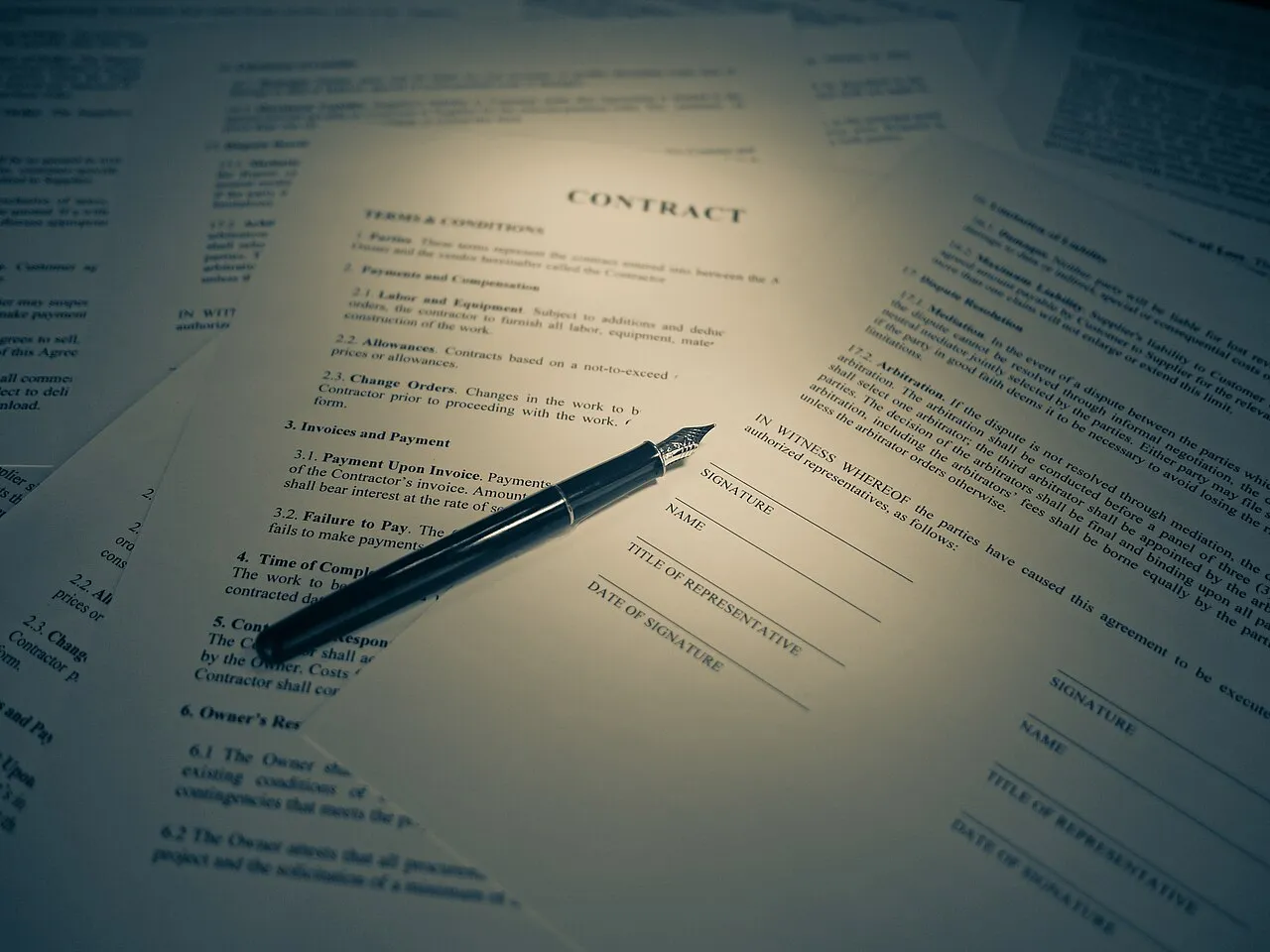A printed contract headed Terms and Conditions with a fountain pen resting on the signature lines