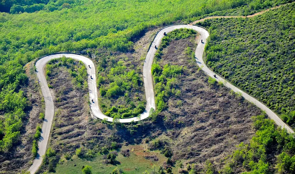A road winding in tight hairpin bends across a green Macedonian hillside