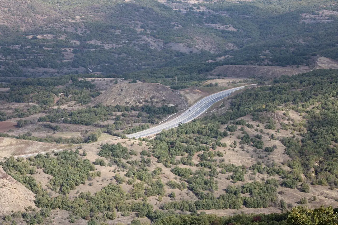 A modern dual-carriageway motorway curving through green hills in North Macedonia