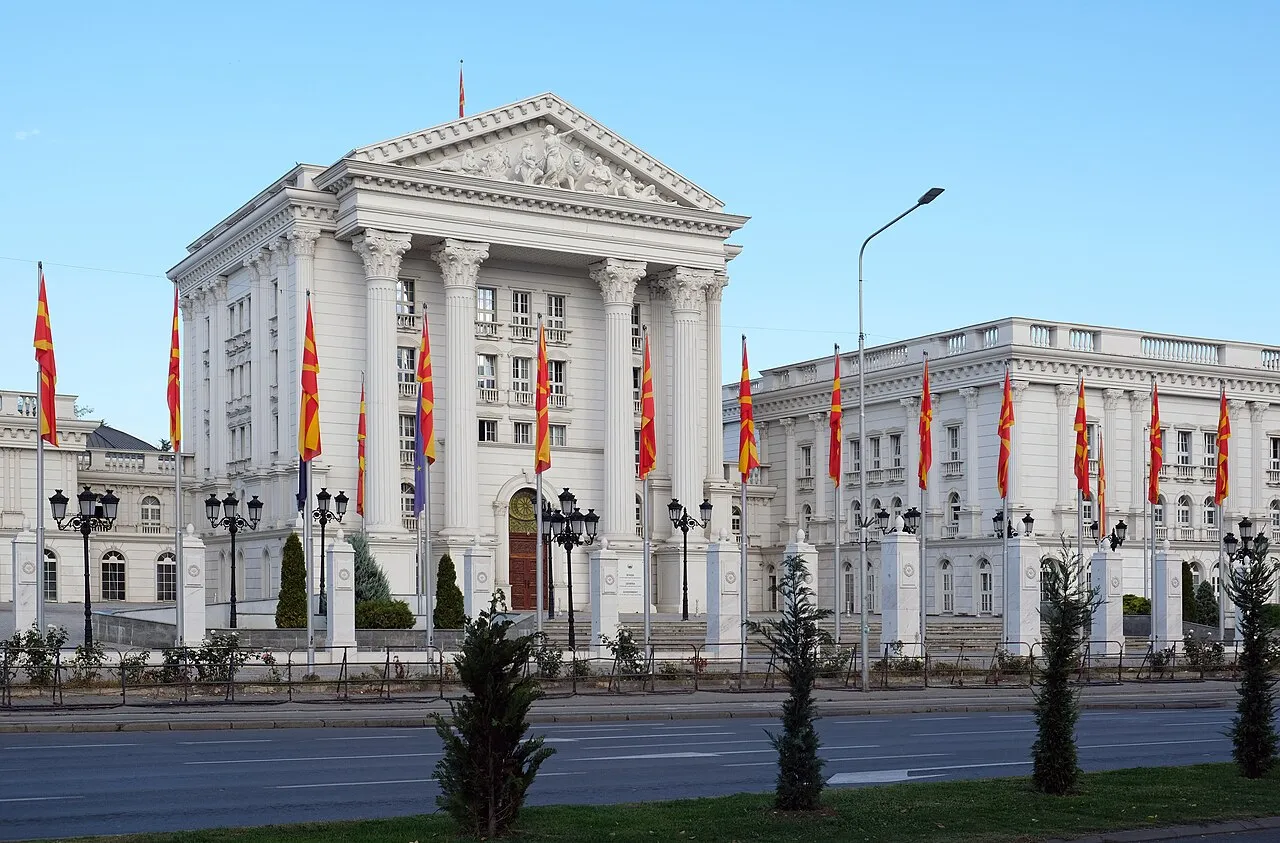 The neoclassical Government Headquarters of North Macedonia in Skopje, flanked by rows of Macedonian flags
