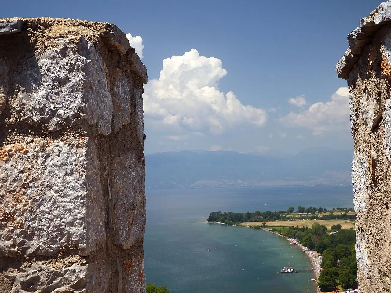 A view of Lake Ohrid and its far shore framed between two stone merlons of the fortress battlement