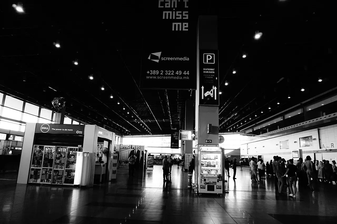 The arrivals area inside Skopje International Airport with shops and waiting passengers